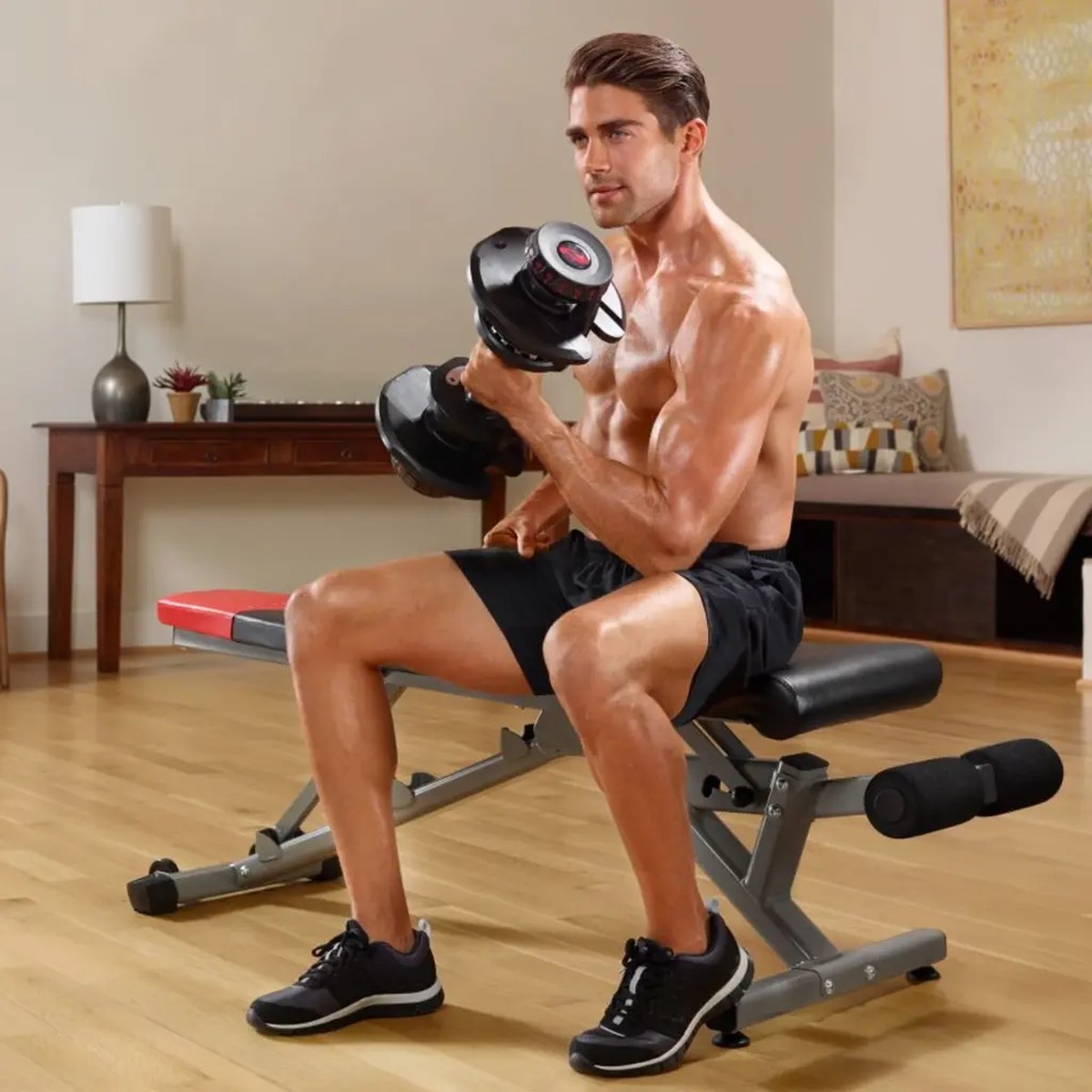 Mann som gjør bicepscurl sittende på en treningsbenk