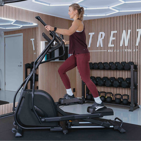Kvinne som trener på crosstraineren i et treningsrom