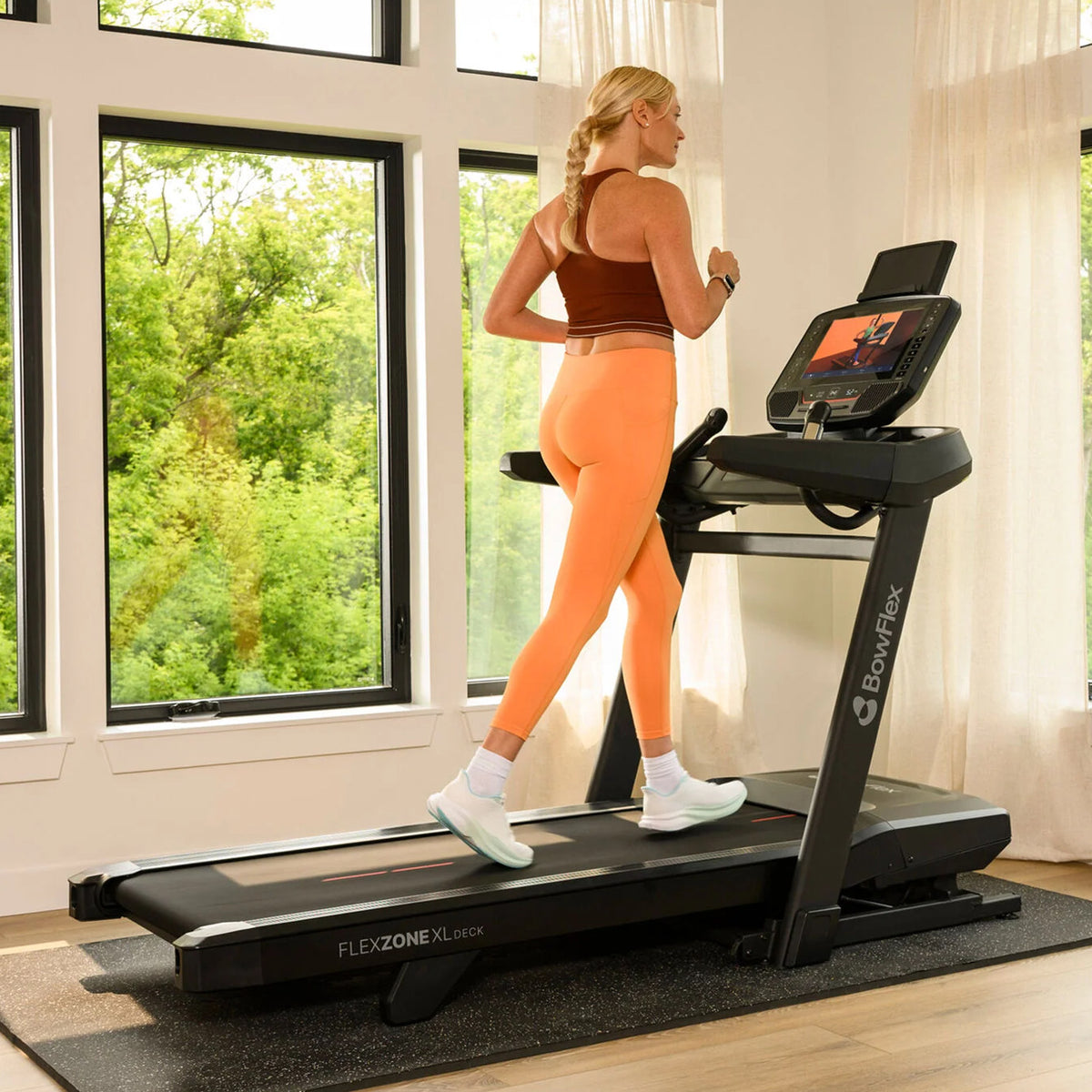 Kvinne som løper på BowFlex T16 tredemølle i en lys stue