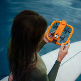 Kvinne med surfebrett som holder HoverAir Aqua